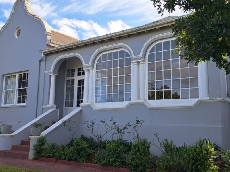 A charming Cape Dutch style home featuring a distinctive gabled facade, arched windows with decorative columns, and a welcoming front staircase.