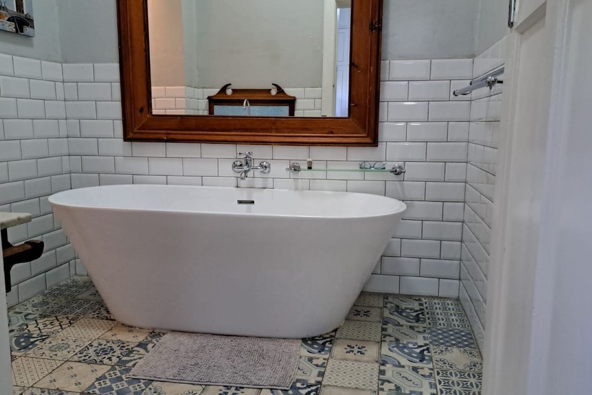 A well-appointed bathroom featuring a modern freestanding bathtub, classic white subway wall tiles, and decorative patterned floor tiles.