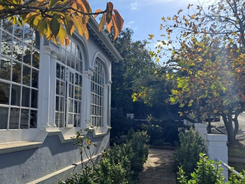 A charming exterior view of the property featuring classic arched windows with decorative detailing, set alongside a stone pathway and mature garden.