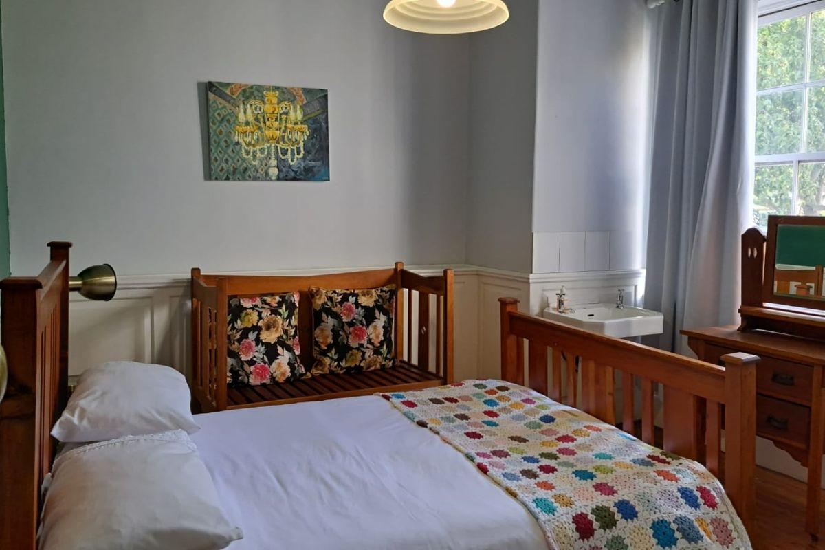 A bedroom featuring wainscoting, a sash window, and a convenient wall-mounted basin.