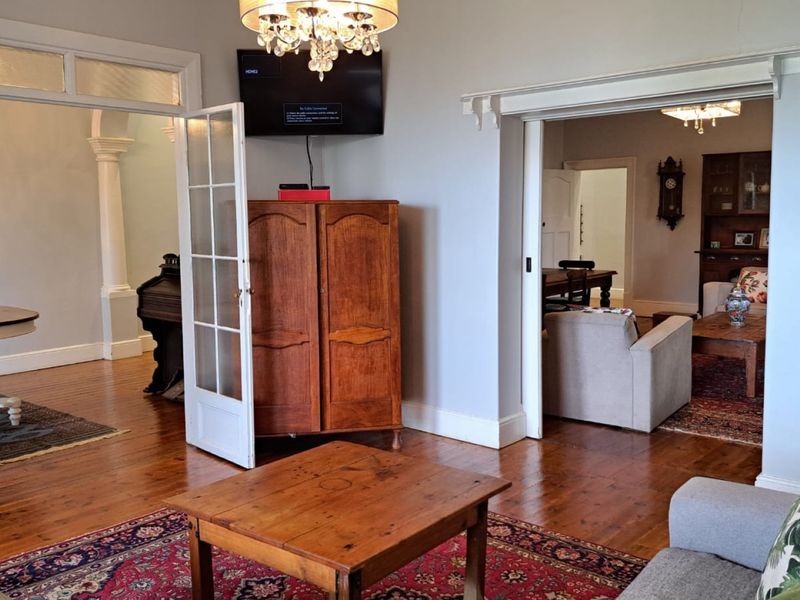 Spacious living area featuring polished hardwood floors, elegant french doors, and classic architectural detailing connecting to adjacent rooms.