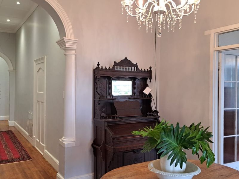 Spacious hallway featuring elegant arched doorways, decorative columns, polished hardwood flooring, and classic architectural detailing with a feature crystal chandelier.