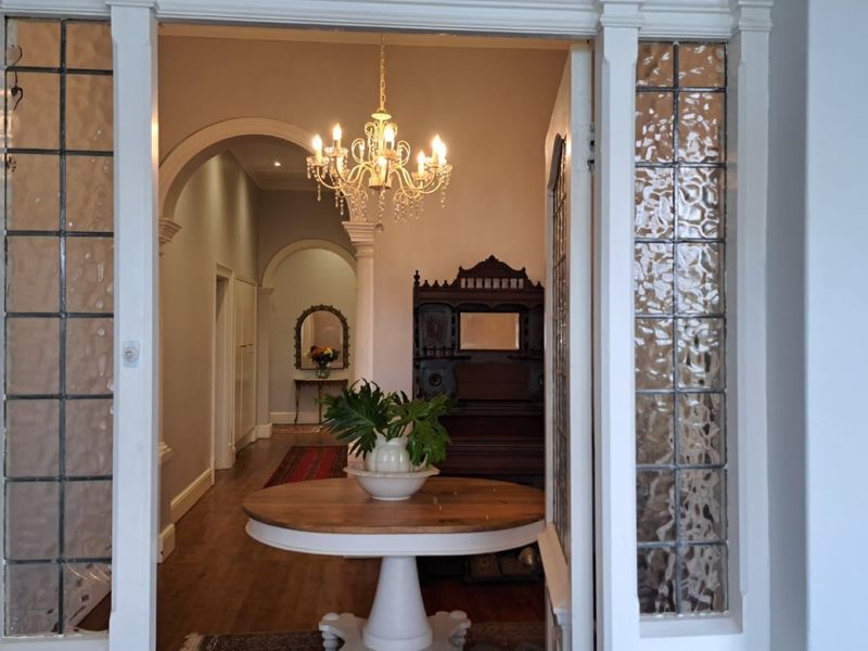 Elegant entrance hall featuring classic archways, hardwood flooring, and a decorative chandelier, framed by traditional leaded glass sidelights.