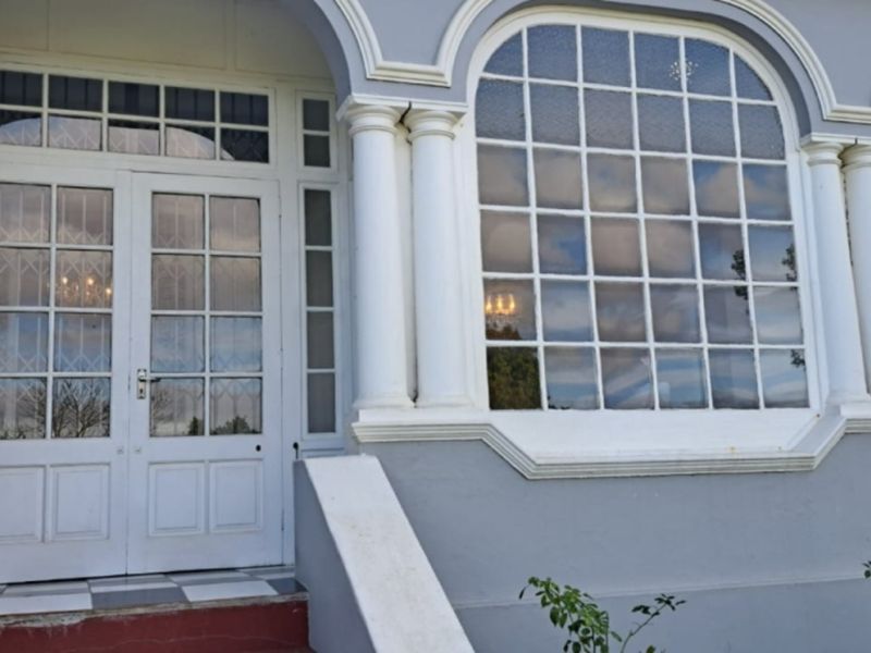 Front entrance featuring classic architectural details, including arched windows, decorative columns, and a double-door entry with a checkered tile porch.