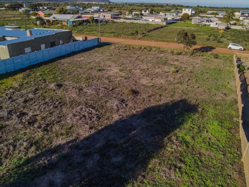 An aerial view of a vacant residential plot featuring established boundary fencing and surrounding neighborhood infrastructure.