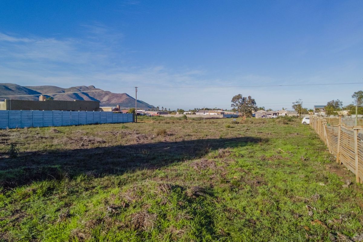 A vacant residential plot featuring a mix of precast concrete and timber boundary fencing with mountain views in the background.