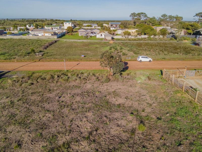 Aerial view of a vacant residential plot featuring natural vegetation and perimeter fencing, situated in a developed neighborhood.