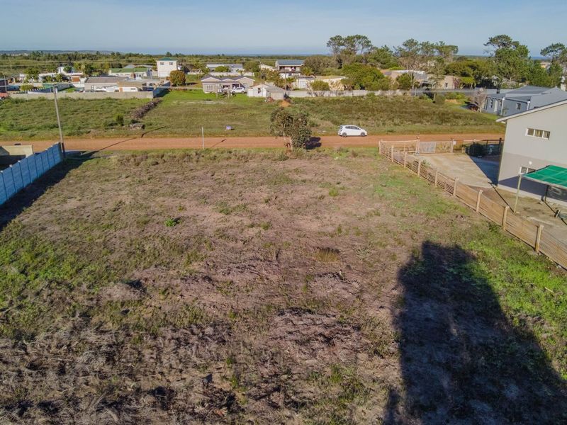 An aerial view of a vacant residential plot featuring boundary fencing and surrounding neighborhood context.