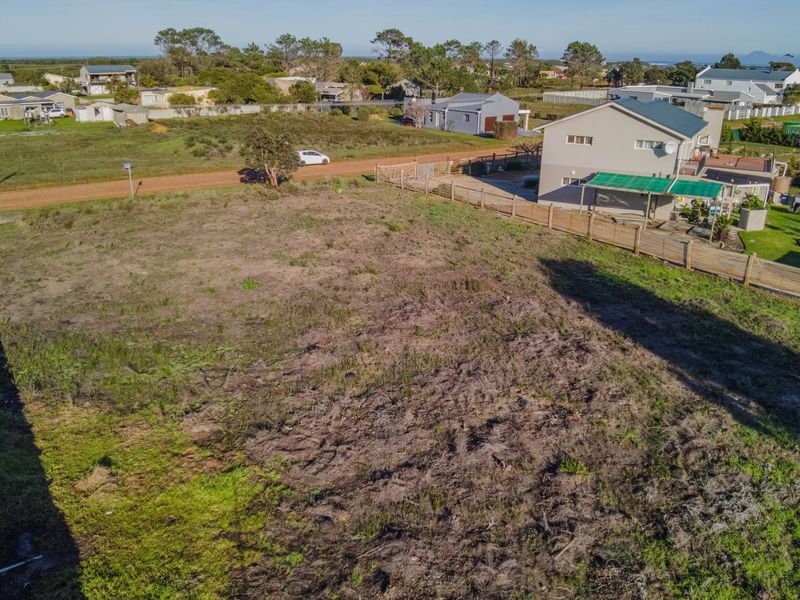 An aerial view of a vacant residential plot of land, showing surrounding neighborhood context and existing boundary fencing.