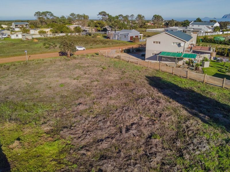 An aerial view of a vacant residential plot of land, showing surrounding neighborhood context and existing boundary fencing.