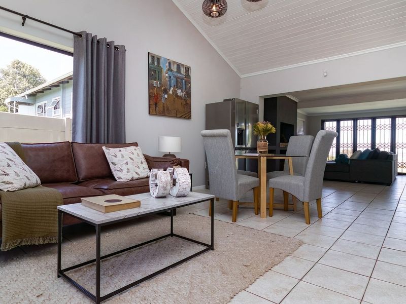 Spacious open-plan living and dining area featuring vaulted ceilings, tiled flooring, and seamless flow to the outdoor space through sliding glass doors.