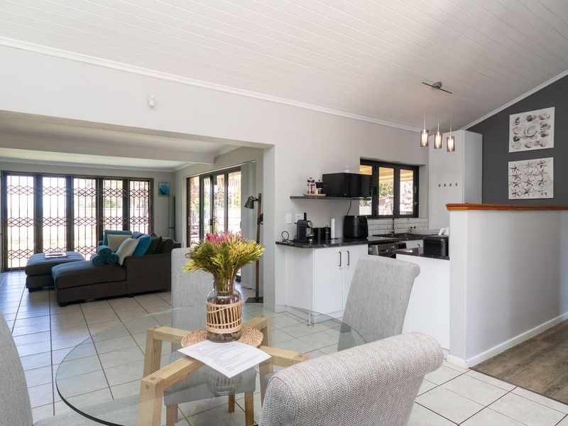 Open-plan living and dining area featuring tiled floors, a modern kitchen with built-in cabinetry, and direct access to the outdoor space via sliding doors.