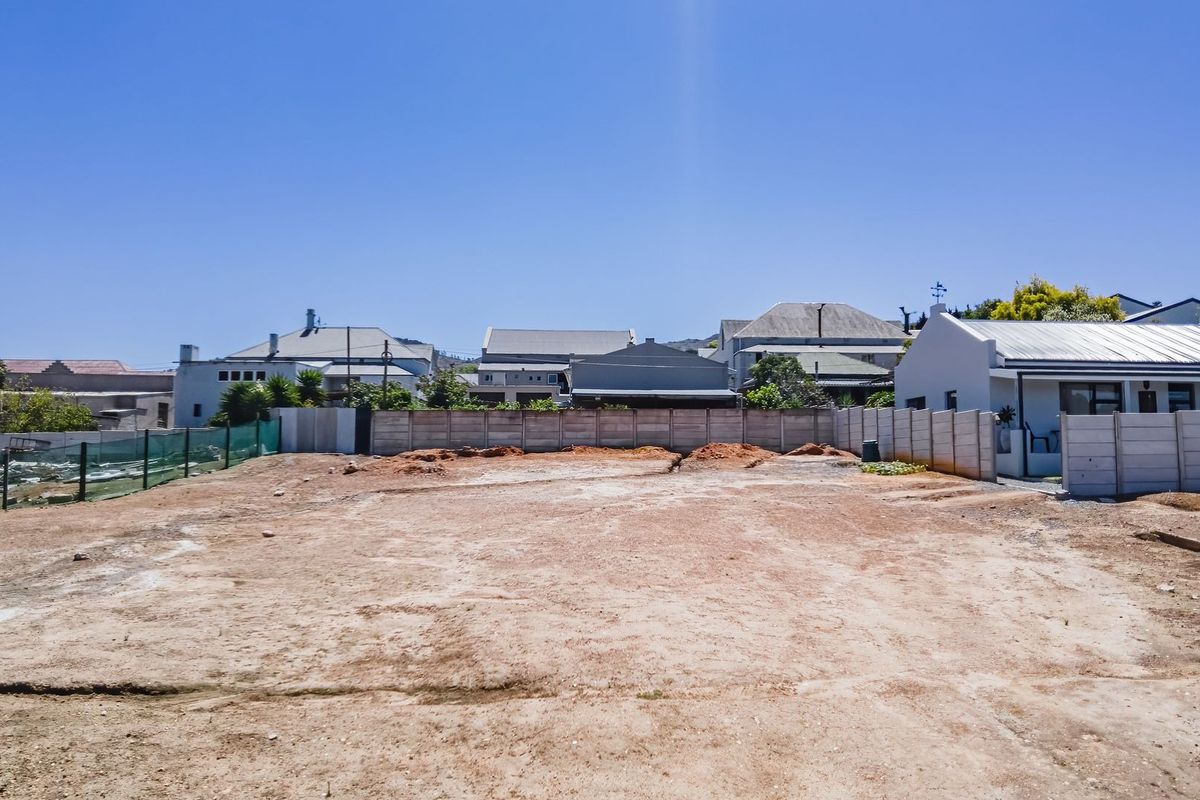 A vacant residential plot featuring a cleared surface and enclosed by precast concrete boundary walls, ready for development.