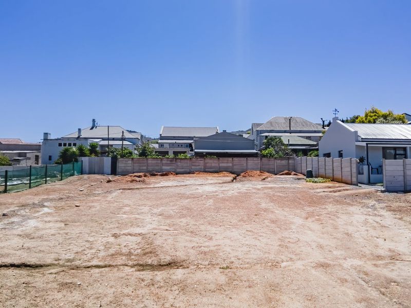 A vacant residential plot featuring a cleared surface and enclosed by precast concrete boundary walls, ready for development.