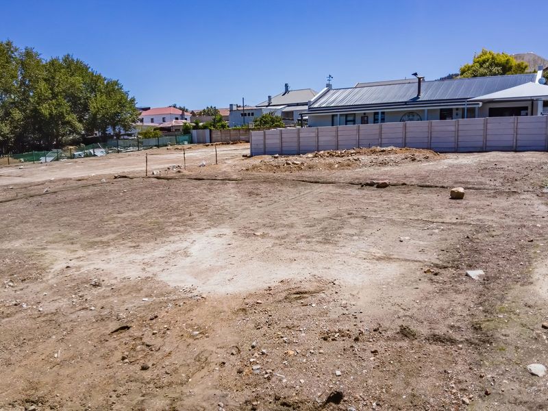A vacant residential plot of land featuring a precast concrete boundary wall, ready for development in a established neighborhood.