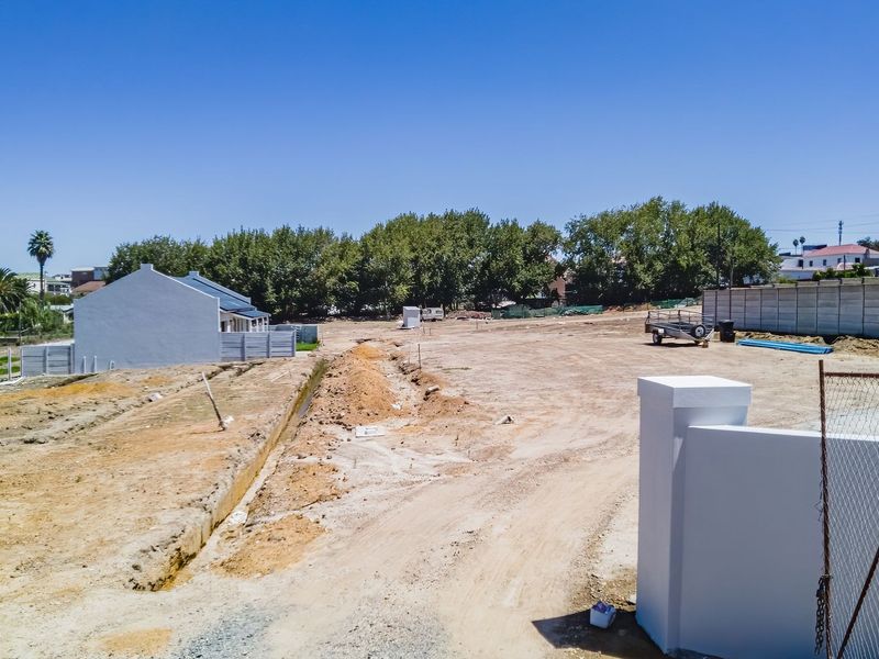 A vacant residential plot featuring boundary walls, entrance pillars, and an excavated trench, ready for development.