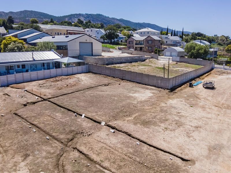 Aerial view of a vacant residential plot featuring cleared land and established precast concrete boundary walls in a suburban setting.