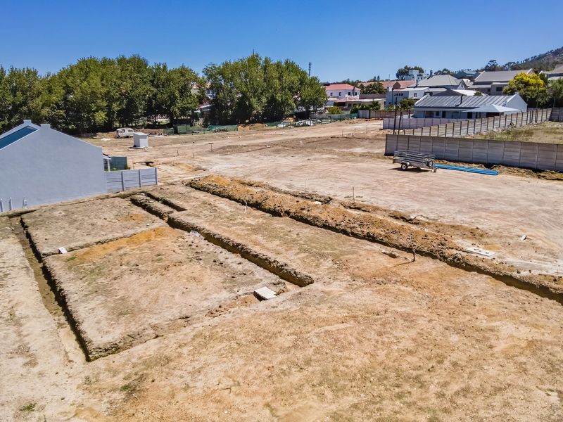 Aerial view of a vacant residential plot featuring excavated foundation trenches and perimeter boundary walling in a developing neighborhood.