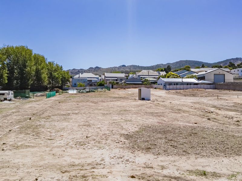 A vacant residential plot of land featuring level ground, boundary fencing, and surrounding neighborhood views, ready for development.
