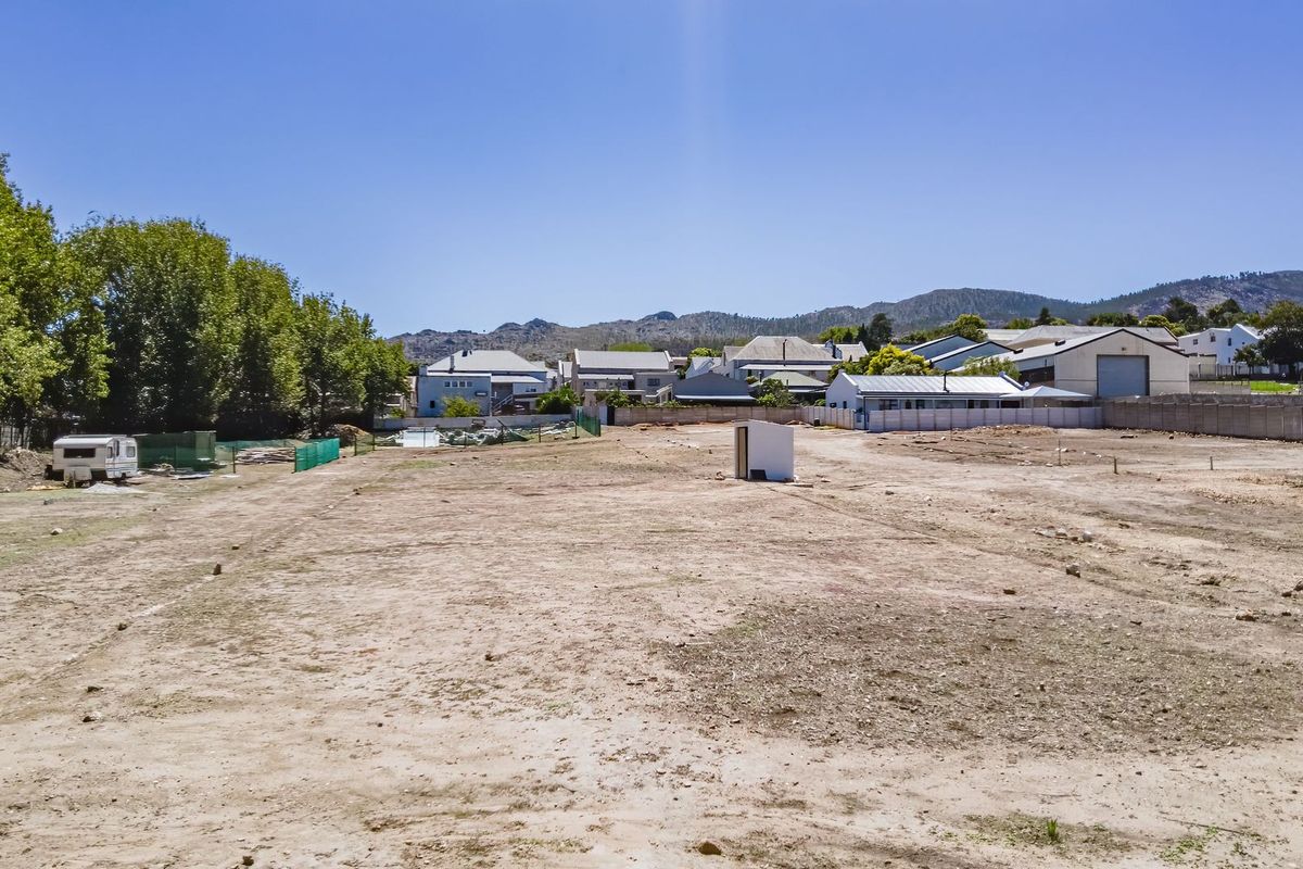 A vacant residential plot of land featuring level ground, boundary fencing, and surrounding neighborhood views, ready for development.