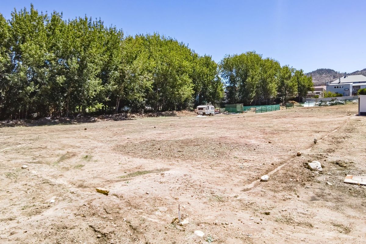 A spacious, cleared residential plot featuring mature trees along the boundary, offering a blank canvas for future development.