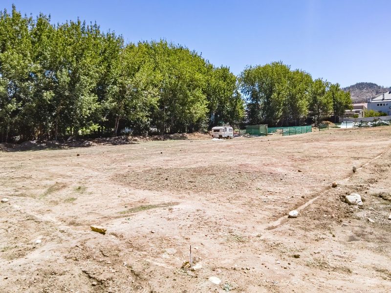 A spacious, cleared residential plot featuring mature trees along the boundary, offering a blank canvas for future development.