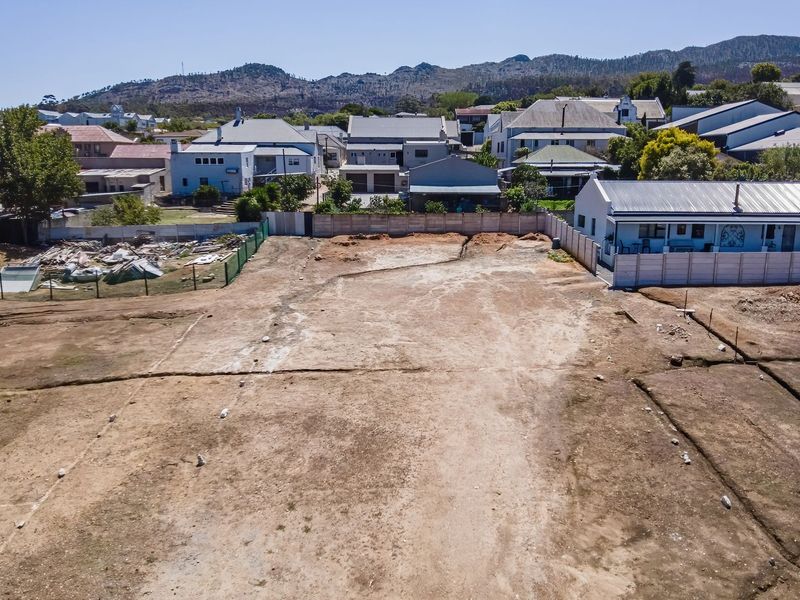 Aerial view of a vacant residential plot featuring a precast concrete boundary wall, ready for development in a established neighborhood.