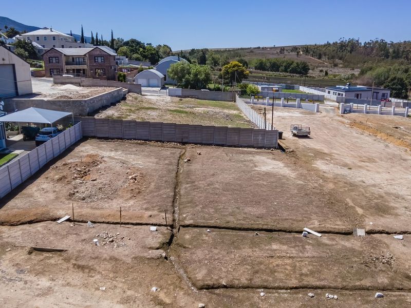 An aerial view of a cleared residential vacant land plot featuring precast concrete boundary walls and visible ground trenching.