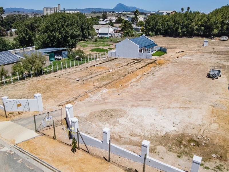 Aerial view of a large, cleared residential vacant land plot featuring perimeter walling and gated access in a suburban setting.
