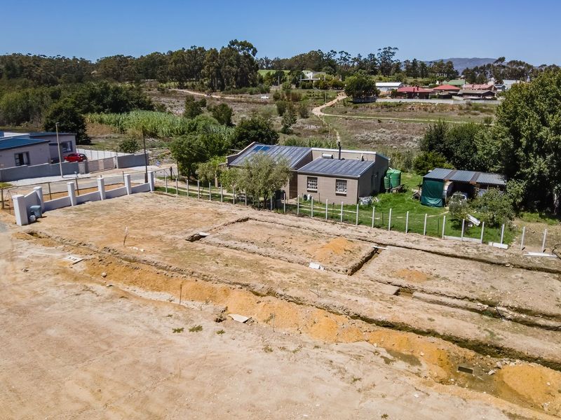 Aerial view of a vacant residential plot featuring excavated foundation trenches and perimeter fencing in a developing neighborhood.
