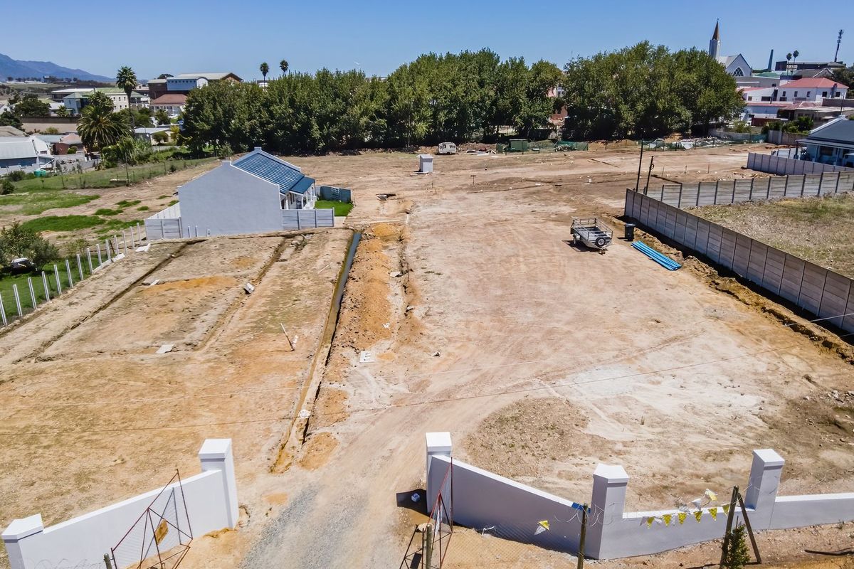 Aerial view of a large, cleared residential vacant land plot featuring perimeter walling and established boundary fencing in a suburban setting.