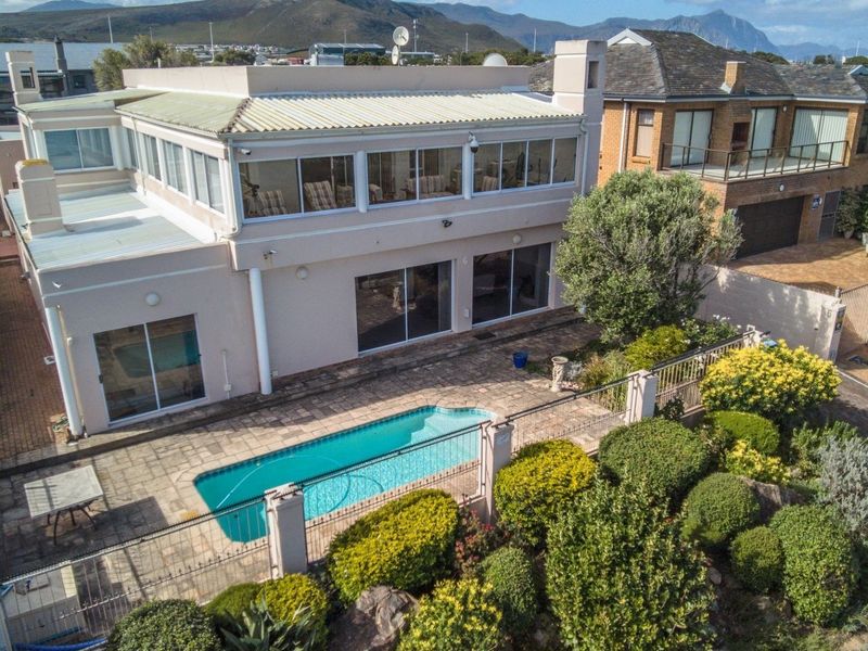 Aerial view of the property featuring a swimming pool, paved patio area, enclosed upper balcony, and established garden landscaping.