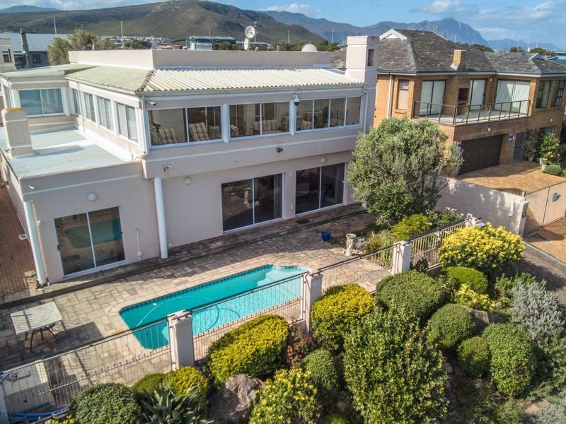 Aerial view of a two-story residence featuring a swimming pool, paved patio area, and established garden, set within a residential neighborhood.