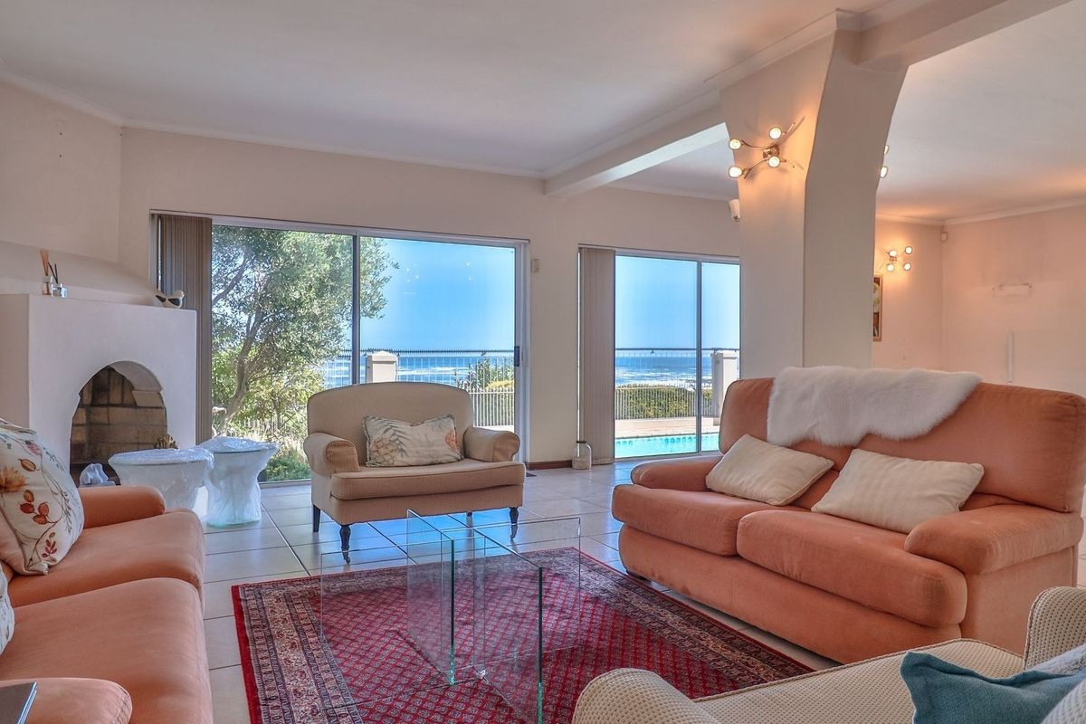 Spacious living room featuring a built-in fireplace, ceramic tile flooring, and large sliding glass doors offering scenic ocean and pool views.