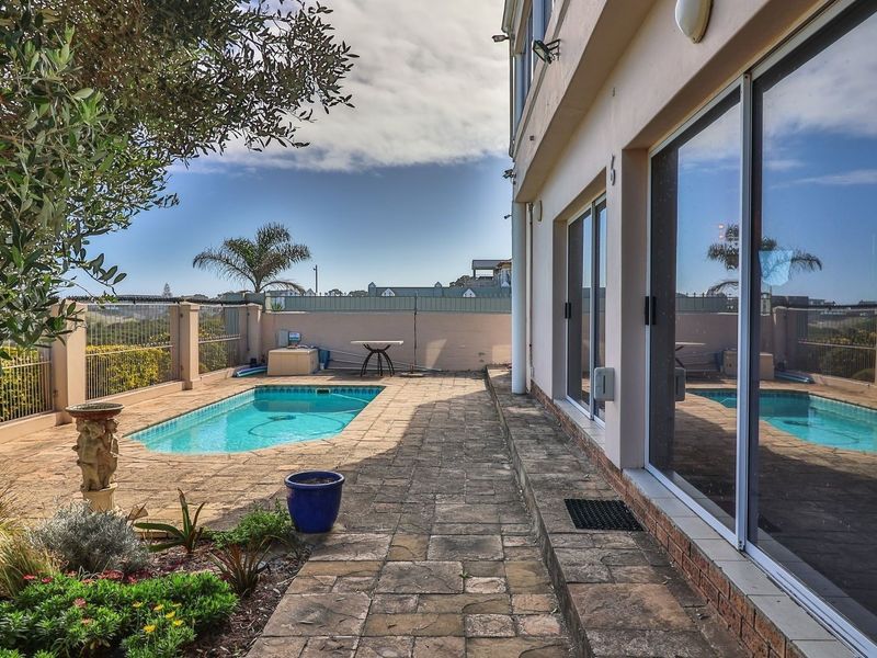 Outdoor pool area featuring a paved patio, swimming pool, and direct access to the home through large sliding glass doors.