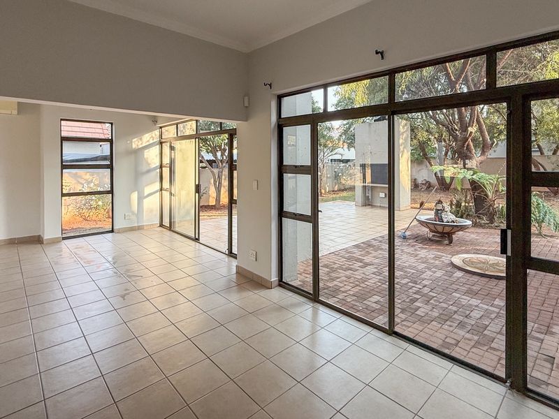 Spacious, light-filled living area featuring neutral tiled flooring and large aluminium sliding doors providing seamless access to the outdoor patio and garden.