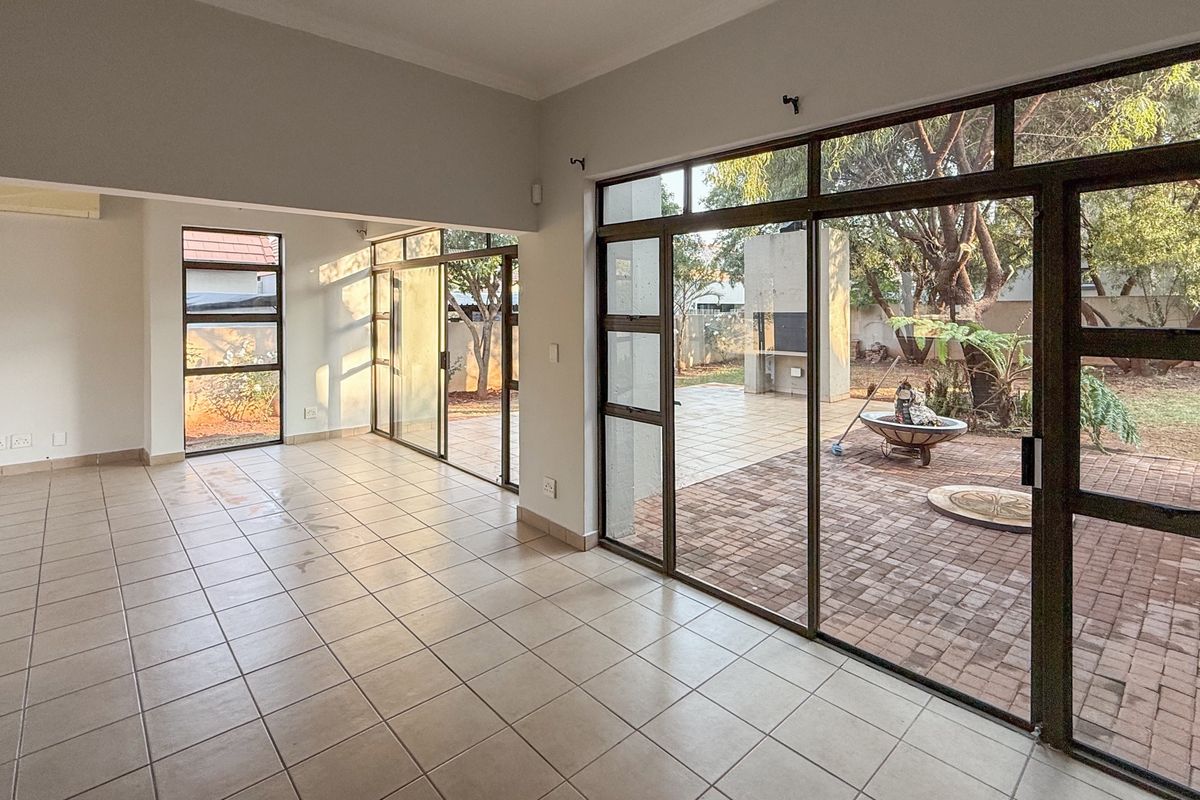 Spacious, light-filled living area featuring neutral tiled flooring and large aluminium sliding doors providing seamless access to the outdoor patio and garden.