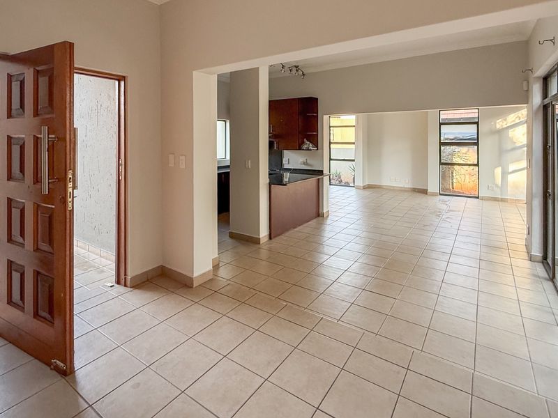 Spacious open-plan living and kitchen area featuring tiled flooring, built-in cabinetry, and large sliding glass doors leading to the exterior.