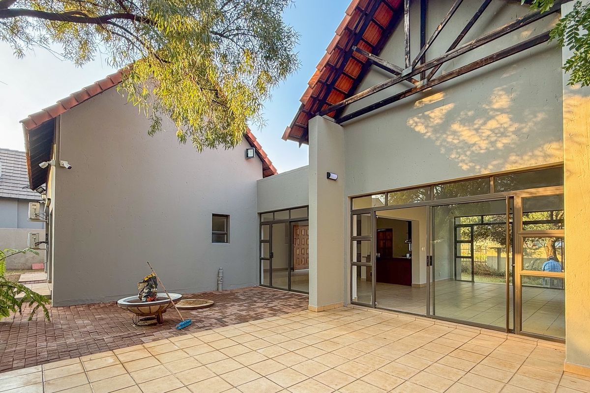 A spacious rear courtyard featuring a tiled patio area, paved sections, and large sliding glass doors providing seamless access to the interior living spaces.