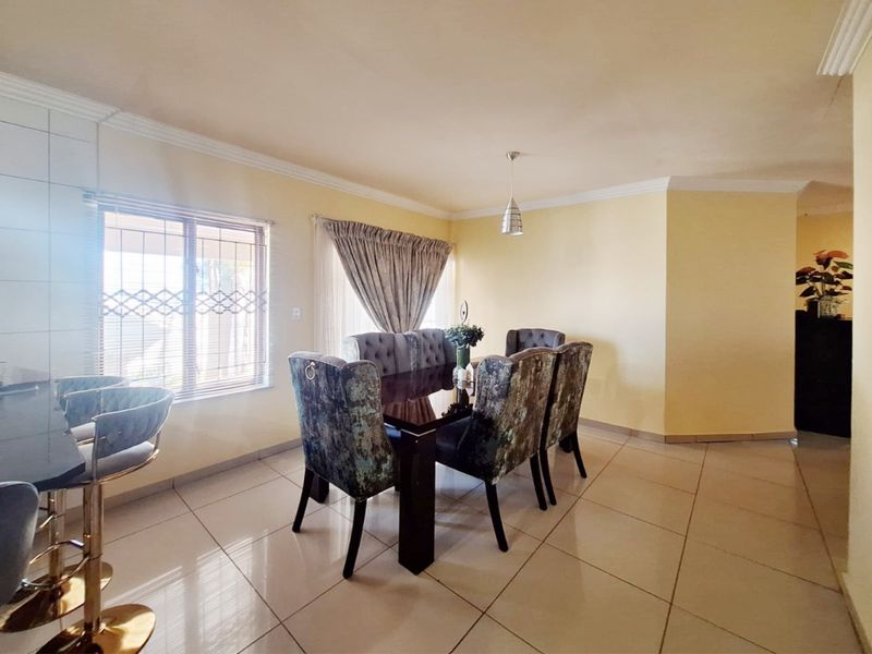 Dining room featuring tiled flooring, security bars on windows, and decorative cove cornicing, providing a functional space for family meals.