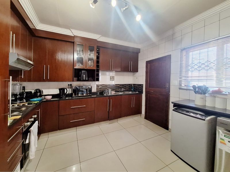 A functional kitchen featuring dark wood cabinetry, granite countertops, tiled flooring, and a built-in oven with an extractor fan.