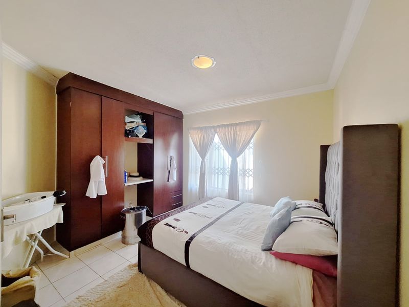 A bedroom featuring tiled flooring, a built-in wooden wardrobe, and a coved ceiling with recessed lighting.