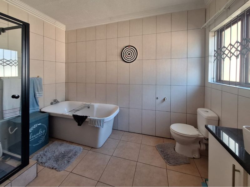 A functional bathroom featuring a freestanding bathtub, separate shower enclosure, toilet, and vanity cabinet with tiled finishes throughout.