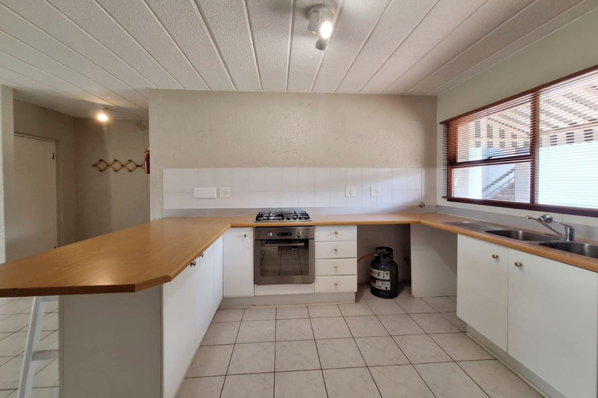 A functional kitchen featuring white cabinetry, laminate countertops, a built-in oven with gas hob, and tiled flooring, offering a clean and practical workspace.