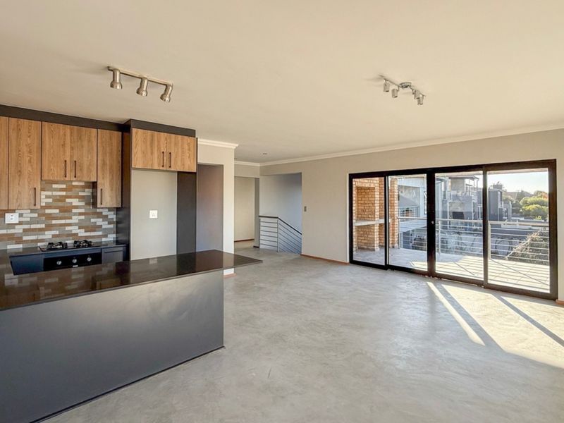 Spacious open-plan living area featuring a modern kitchen with granite countertops, gas hob, and seamless flow to a balcony through large sliding glass doors.