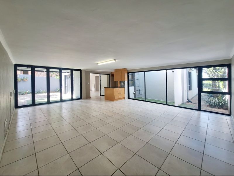 Spacious open-plan living area featuring large glass sliding doors that provide abundant natural light and seamless access to the outdoor patio and garden.