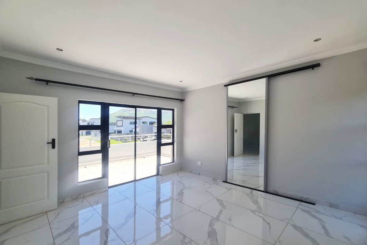 A bright, modern bedroom featuring large-format marble-look floor tiles, a built-in sliding mirror wardrobe, and a sliding glass door leading to an outdoor balcony.