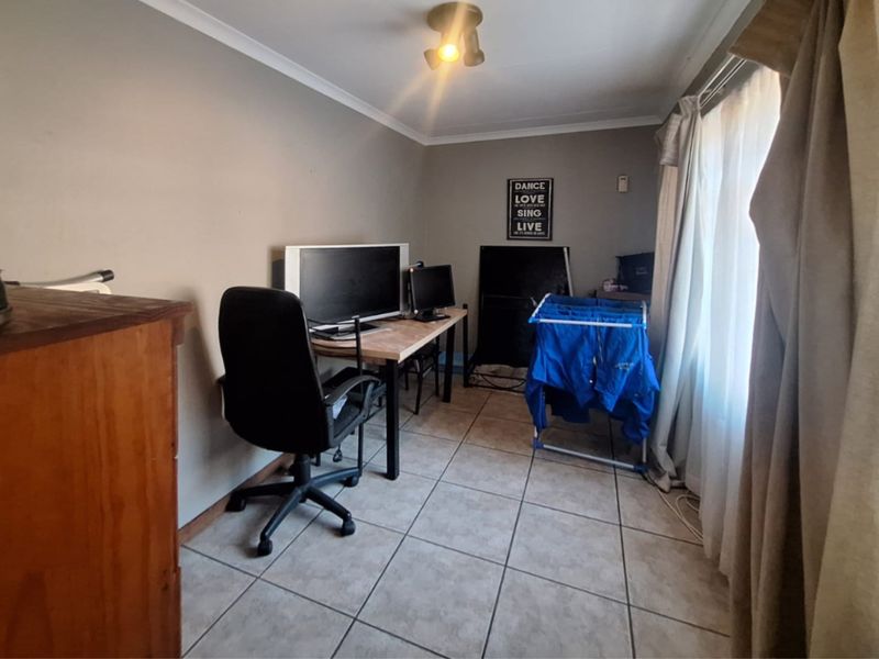A functional home office space featuring neutral wall tones and tiled flooring, offering a versatile area for work or study.