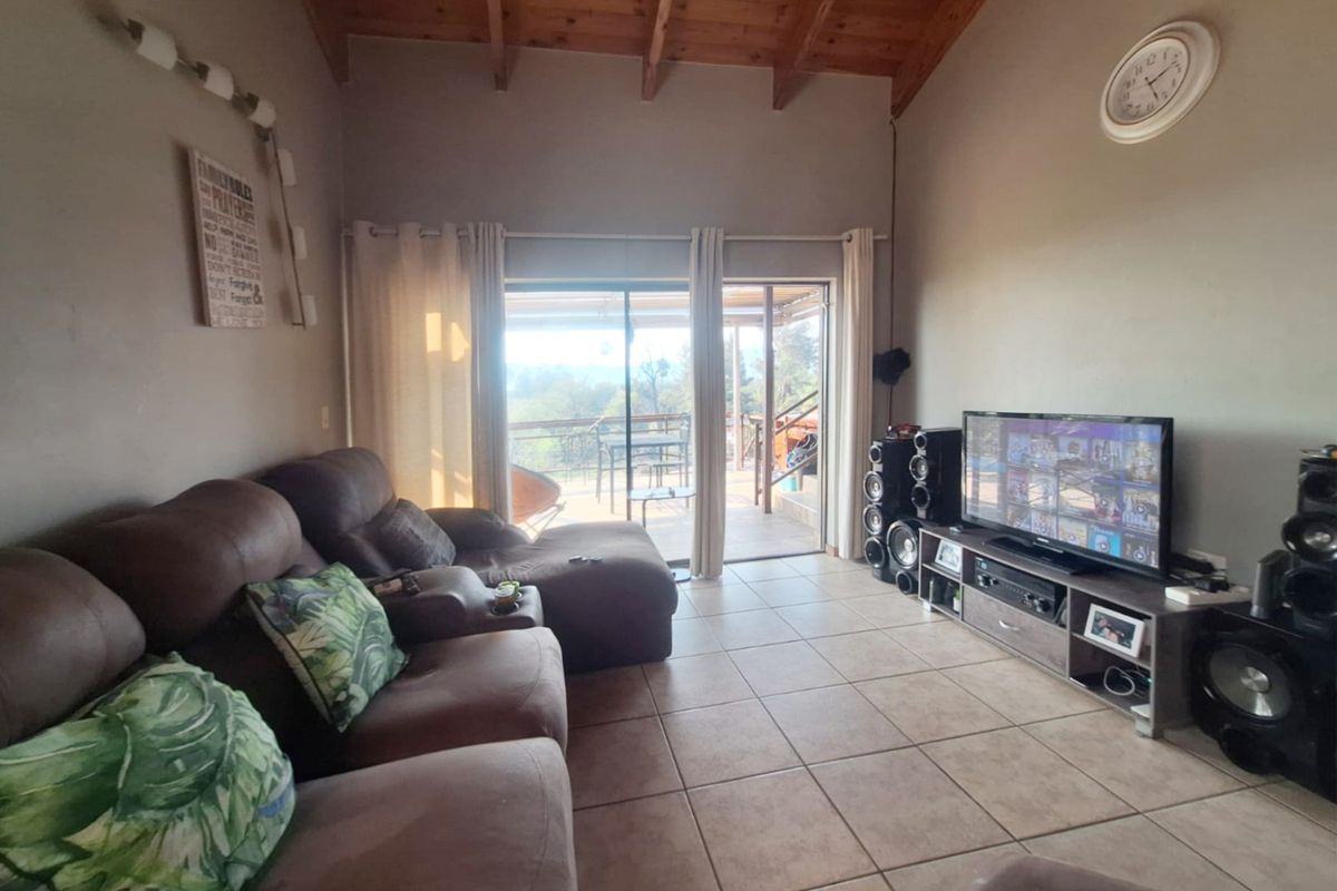 Spacious living room featuring high exposed timber beam ceilings, ceramic tiled flooring, and direct access to an outdoor patio through sliding glass doors.