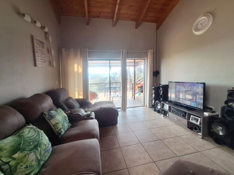 Spacious living room featuring high exposed timber beam ceilings, ceramic tiled flooring, and direct access to an outdoor patio through sliding glass doors.